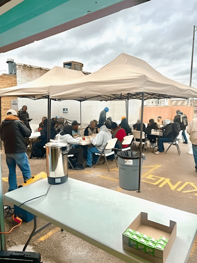 People eating under tents at outdoor food distribution